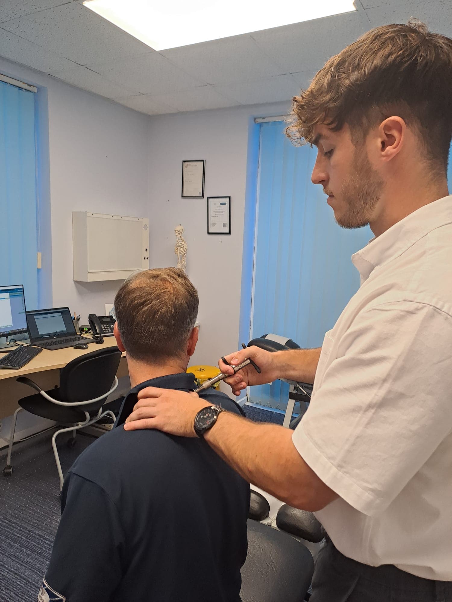An adjustment being made with an instrument at Frameworks Clinic, the patient sitting upright and fully clothed