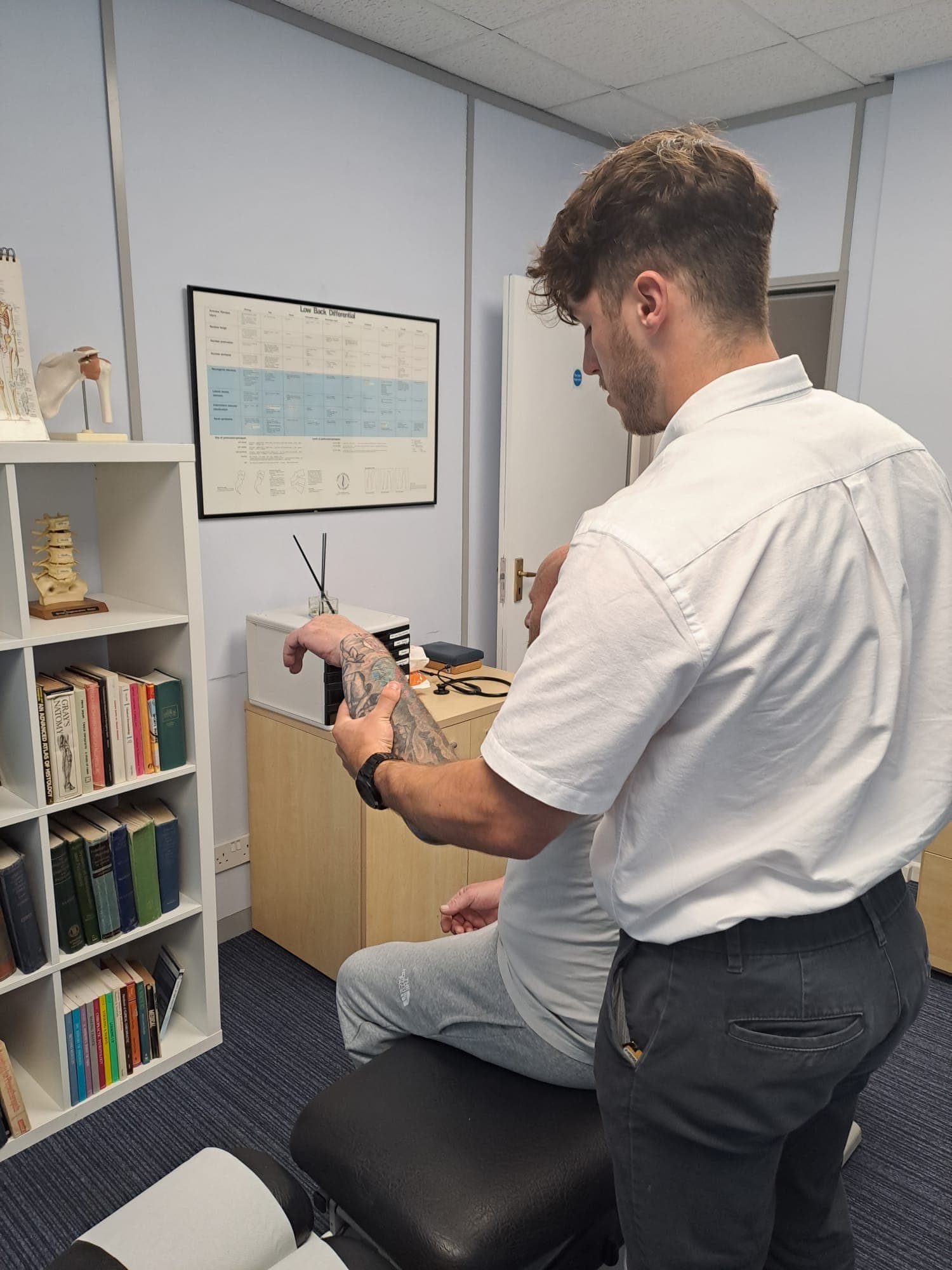 A shoulder being examined at Frameworks Clinic, the patient seated and fully clothed